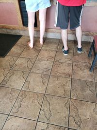 Low section of people standing on tiled floor