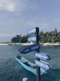 Information sign by sea against sky