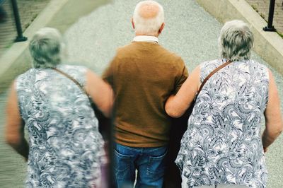 Rear view of senior people standing by mirror on street in city