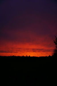 Silhouette landscape against dramatic sky during sunset