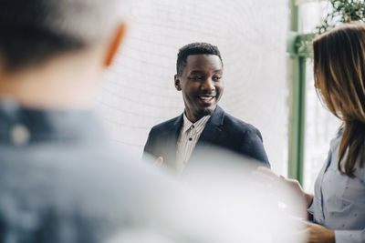 Smiling businessman discussing with coworkers at conference