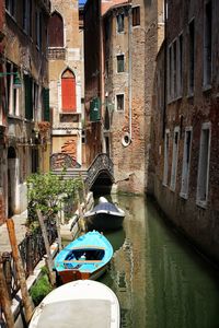 Boats in canal amidst buildings