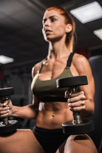 Mid adult woman holding dumbell at the gym during workout