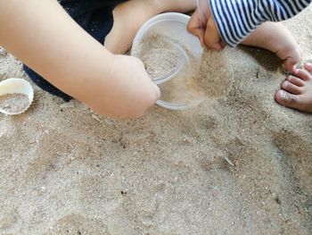 Low section of woman relaxing on sand at beach