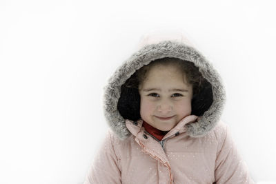 Little girl age 5 years old in pink winter jacket posing to camera .background white snow