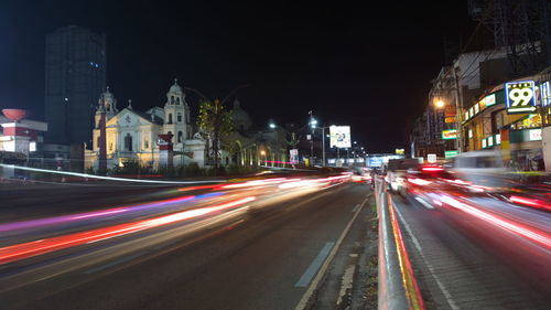 Light trails on city street by buildings at night