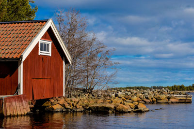 House by lake and building against sky