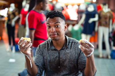 Portrait of man having durian while sitting in store