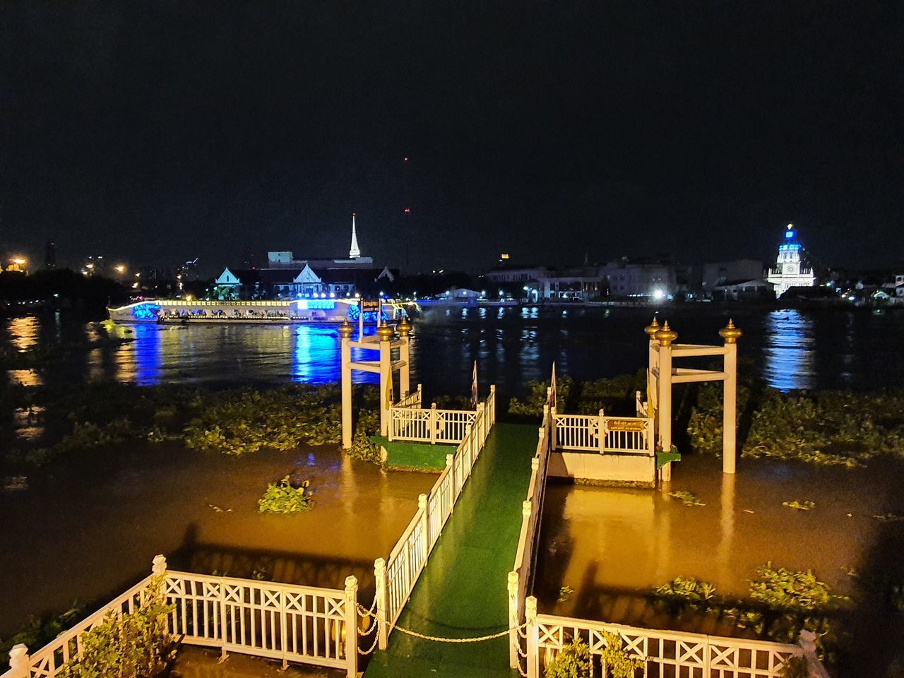 ILLUMINATED BUILDINGS BY RIVER AGAINST SKY