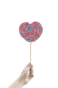 Close-up of hand holding ice cream against white background