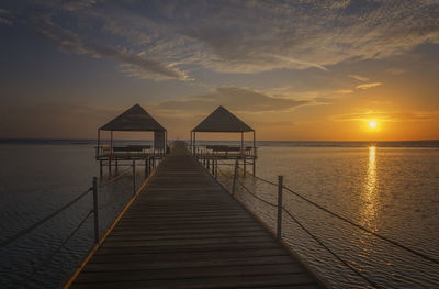 Pier over sea against sky during sunset