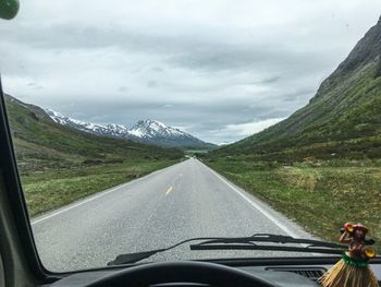 Road amidst mountains seen through car windshield