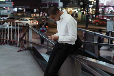 Side view of man using mobile phone in city