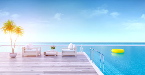 Empty lounge chairs by infinity pool against sky