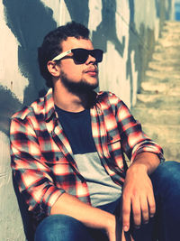 Young man wearing sunglasses sitting outdoors