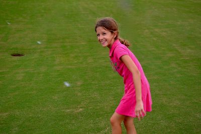 Side view of smiling young woman standing on grassy field