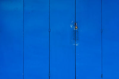 Low angle view of lighting equipment hanging against blue wall