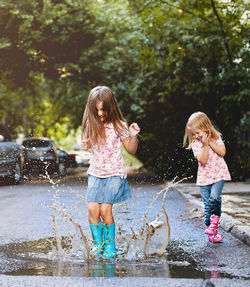Full length of girls playing in puddle