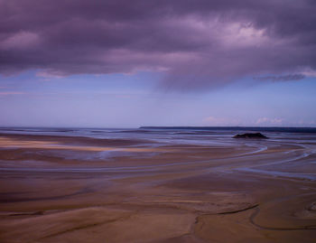 Scenic view of beach and sea against cloudy sky