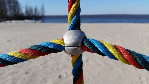 Close-up of multi colored tied hanging on rope against sea