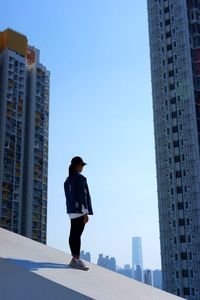 Low angle view of woman standing against buildings in city