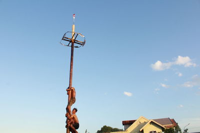 Low angle view of man holding building against sky