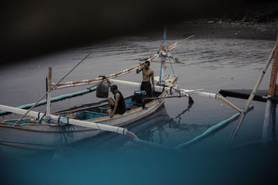 Fishing boats moored in sea against sky