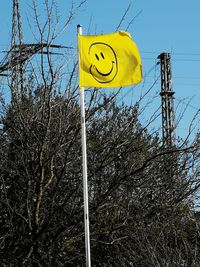 Low angle view of yellow sign against sky