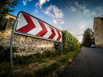 Road sign on field against sky