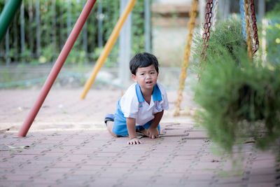 Portrait of boy crying while kneeling on footpath