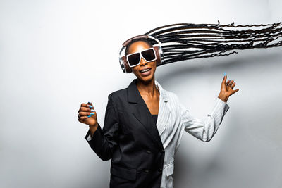 Young woman wearing sunglasses standing against white background