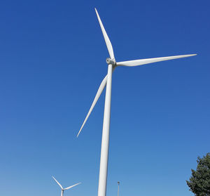 Low angle view of wind turbine against clear blue sky