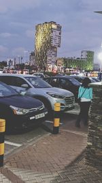 Vehicles on road by buildings in city against sky