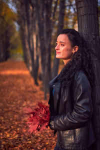 Woman standing on tree trunk in forest during autumn