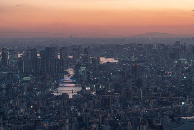 Illuminated cityscape against sky during sunset
