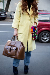 Woman holding umbrella while walking on street