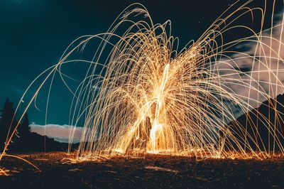 Man making wire wool against sky at night