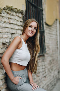 Portrait of beautiful young woman leaning on wall