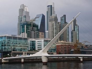 Modern buildings by river against sky in city