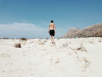 Rear view of woman standing against clear blue sky