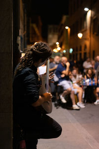 Man holding umbrella while standing on street in city at night