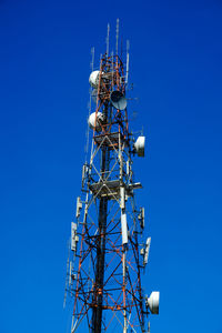 Low angle view of communications tower against clear blue sky