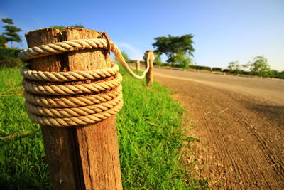 Close-up of wooden post on field against sky