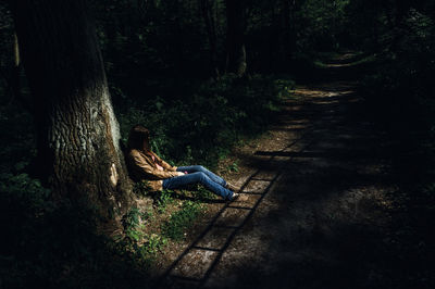 Man sitting on tree trunk in forest