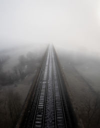 Aerial landscape above railway tracks on an old viaduct disappearing into the fog in the distance