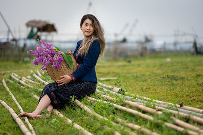 Young woman sitting on pink flowering plant