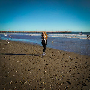 Full length of woman standing on beach against clear sky