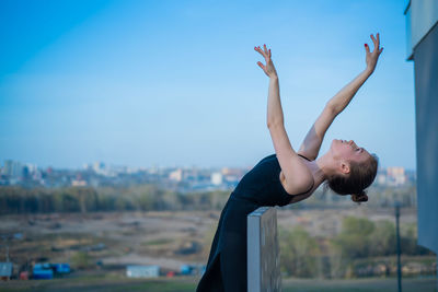 Woman with arms raised against sky