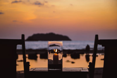 Wine glass on table against sea during sunset