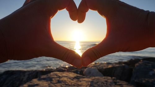 Close-up of hand holding sun over sea